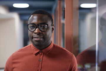 Head and shoulders portrait of contemporary African-American man wearing glasses and looking at...