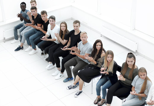 diverse young people applauding while sitting in the same row