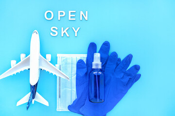 Fototapeta premium Travel after pandemic. Open sky after coronavirus. Plane, Blue passport with medical mask, Protective gloves, Bottle of Hand Sanitizer. Creative flat lay safety travel concept. With space for text.