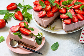 Summer diet dessert, cheesecake without baking. Strawberry cheesecake on a chocolate granola with fresh strawberries on a light gray table top. Copy space.