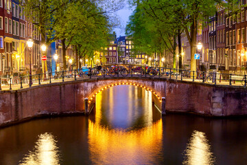 Fototapeta na wymiar Amsterdam canal with typical dutch houses during twilight blue hour in Holland, Netherlands.