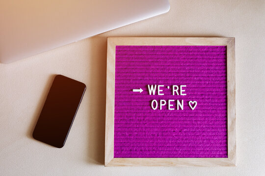 # Reopening plan text on purple letter board near the notebook. Business concept. Service, restaurant, shop and cafe re-opening. Reopening of the place after the quarantine due to covid-19. We're open