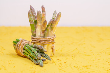 Green and white fresh asparagus on a yellow background