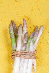Green and white fresh asparagus on a yellow background