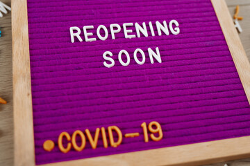 Reopening soon text on purple letter board. Business concept. Service, restaurant, shop and cafe re-opening. Reopening of the place after the quarantine due to covid-19. Message. New rules, we're open