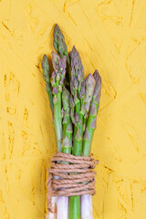 Green and white fresh asparagus on a yellow background