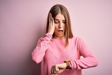 Young beautiful redhead woman wearing casual sweater over isolated pink background Looking at the...