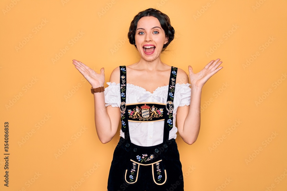 Wall mural Young beautiful german woman with blue eyes wearing traditional octoberfest dress celebrating crazy and amazed for success with arms raised and open eyes screaming excited. Winner concept