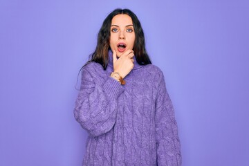 Young beautiful woman wearing casual turtleneck sweater standing over purple background Looking fascinated with disbelief, surprise and amazed expression with hands on chin