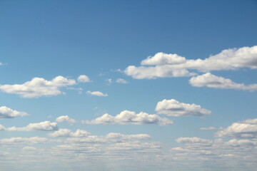 White fluffy clouds on a background of blue sky in summer. The concept of weather and climate.