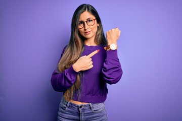 Young beautiful smart woman wearing glasses over purple isolated background In hurry pointing to...