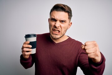 Young man with blue eyes drinking coffee from take away plastic bottle over isolated background annoyed and frustrated shouting with anger, crazy and yelling with raised hand, anger concept