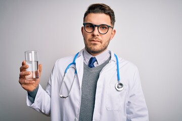 Young doctor man wearing medical coat holding a glass of fresh water over isolated background with a confident expression on smart face thinking serious