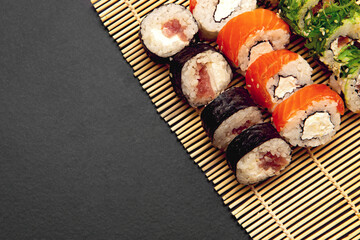 set of sushi roll on a bamboo plate or mat on a black background.