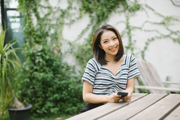 beautiful girl sitting in the Park on a bench, holding smart phone on a Sunny summer day