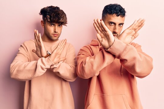 Young gay couple wearing casual clothes rejection expression crossing arms doing negative sign, angry face