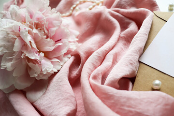 romantic composition. pink peonies on a background of pink silk and pearls