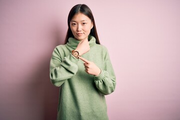 Young beautiful asian woman wearing green winter sweater over pink solated background In hurry...