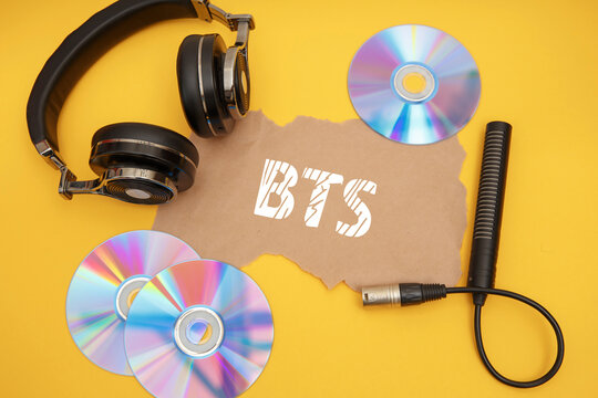 BTS concept with headphones and music discs on a yellow background.