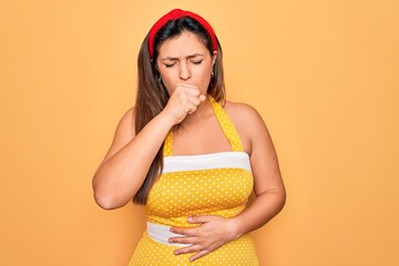 Obraz premium Young hispanic pin up woman wearing fashion sexy 50s style over yellow background feeling unwell and coughing as symptom for cold or bronchitis. Health care concept.