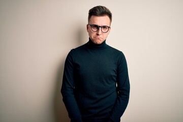 Fototapeta premium Young handsome caucasian man wearing glasses and casual sweater over isolated background skeptic and nervous, frowning upset because of problem. Negative person.