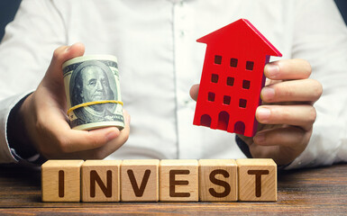 A man with dollars and a house figurine and the word Invest. Real estate financial investment....