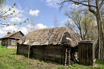 Fototapeta na wymiar Kudrichi, Belarus 04/27/2020: Old houses and sheds with a roof covered with reeds using old-fashioned technology in the Polesie region in the south-west of Belarus.