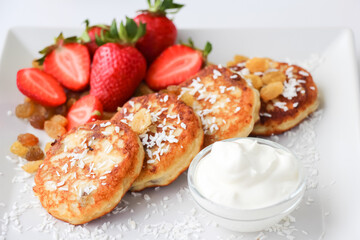 Cottage cheese pancakes with fresh strawberries, raisins and coconut for breakfast
