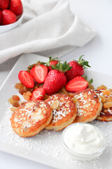 Cottage cheese pancakes with fresh strawberries, raisins and coconut for breakfast
