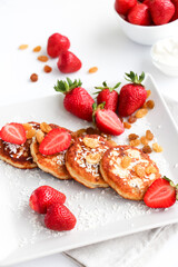 Cottage cheese pancakes with fresh strawberries, raisins and coconut for breakfast
