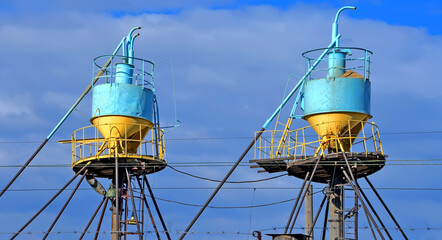large color grain bin bunker (dispenser and dryer) behind the wires at elevator on blue sky in...