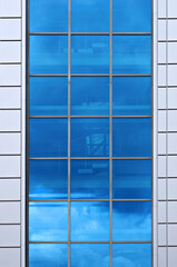 Facade of modern building. Reflection of blue sky in window.