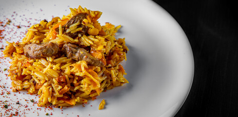 Rice with Vegetables and Meat in white plate on black wooden table background