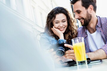 Portrait of young attractive couple looking at their pictures on camera
