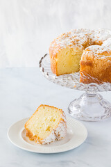 A close up view of Lemon Bundt Cake on a cake stand with a slice of cake in front ready for eating.