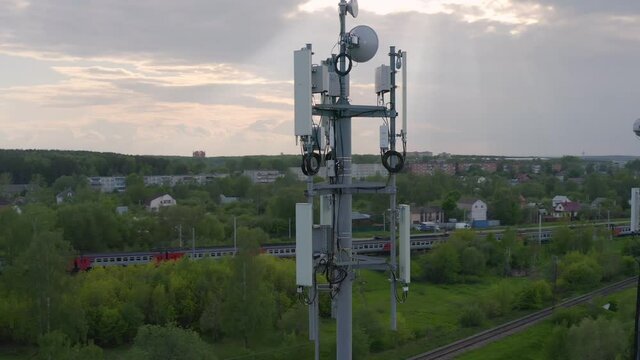 Aerial view of cell tower on the background of passing trains by rail.