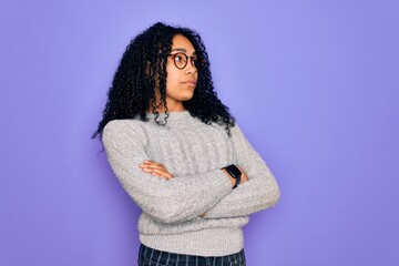 Young african american woman wearing casual sweater and glasses over purple background looking to the side with arms crossed convinced and confident