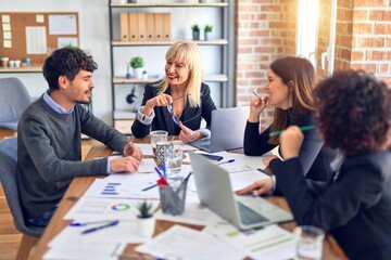 Group of business workers smiling happy and confident. Working together with smile on face  using laptop and speaking at the office