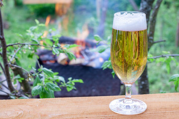 glass glass with cold beer on a warm evening in nature. beer on the background of a burning fire in the grill