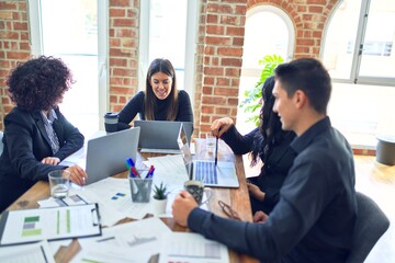 Group of business workers smiling happy and confident. Working together with smile on face  using laptop and speaking at the office