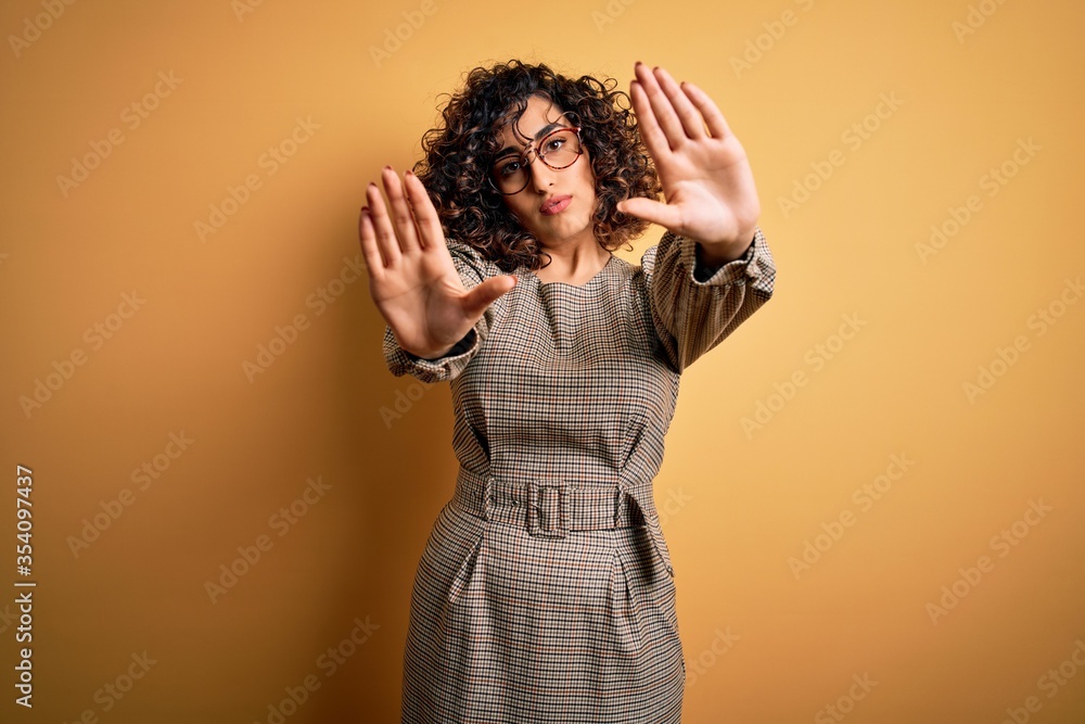 Sticker Beautiful arab business woman wearing dress and glasses standing over yellow background doing frame using hands palms and fingers, camera perspective