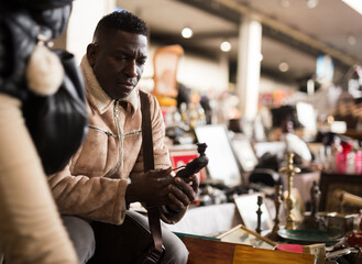 African American man chooses antiques on the flea market
