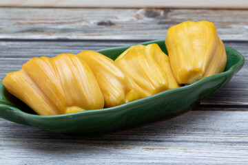 Jackfruit ripe yellow fruit flesh in green plate on wooden table.