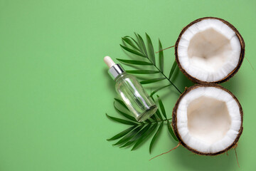 top view cosmetic oil bottle ,coconut and tropical leaf on a green background
