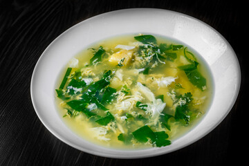 Green Sorrel soup in white plate on black wooden table background