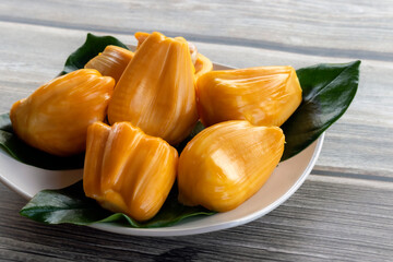 Jackfruit yellow fruit flesh in white plate on wooden table.