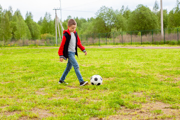 Obraz premium a boy on the Playground playing with a football with a ball. sports, football, children's entertainment