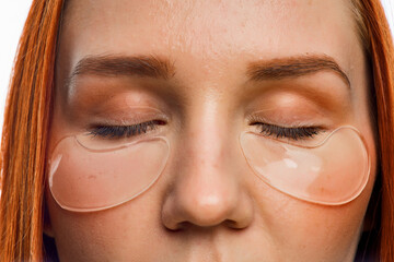 close beauty portrait of a red-haired girl with clean skin and patches under her eyes. Isolated on...