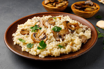 Traditional italian cuisine meal - vegetarian risotto with mushrooms. Black stone backround.