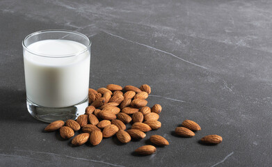 Close up glass of milk with almonds nut on table.